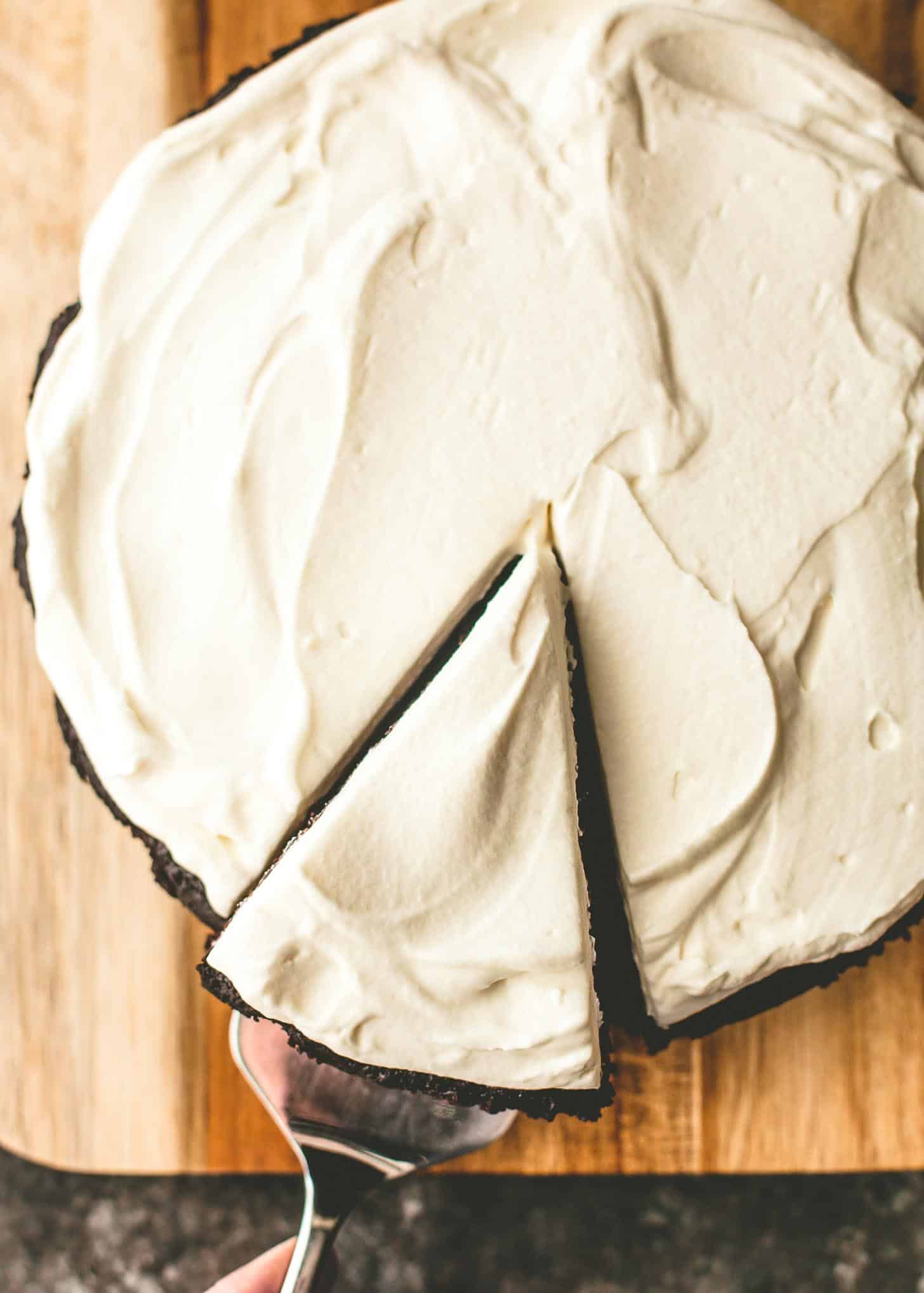 overhead image of using a a pie server to remove a slice from a round chocolate Guinness cake 