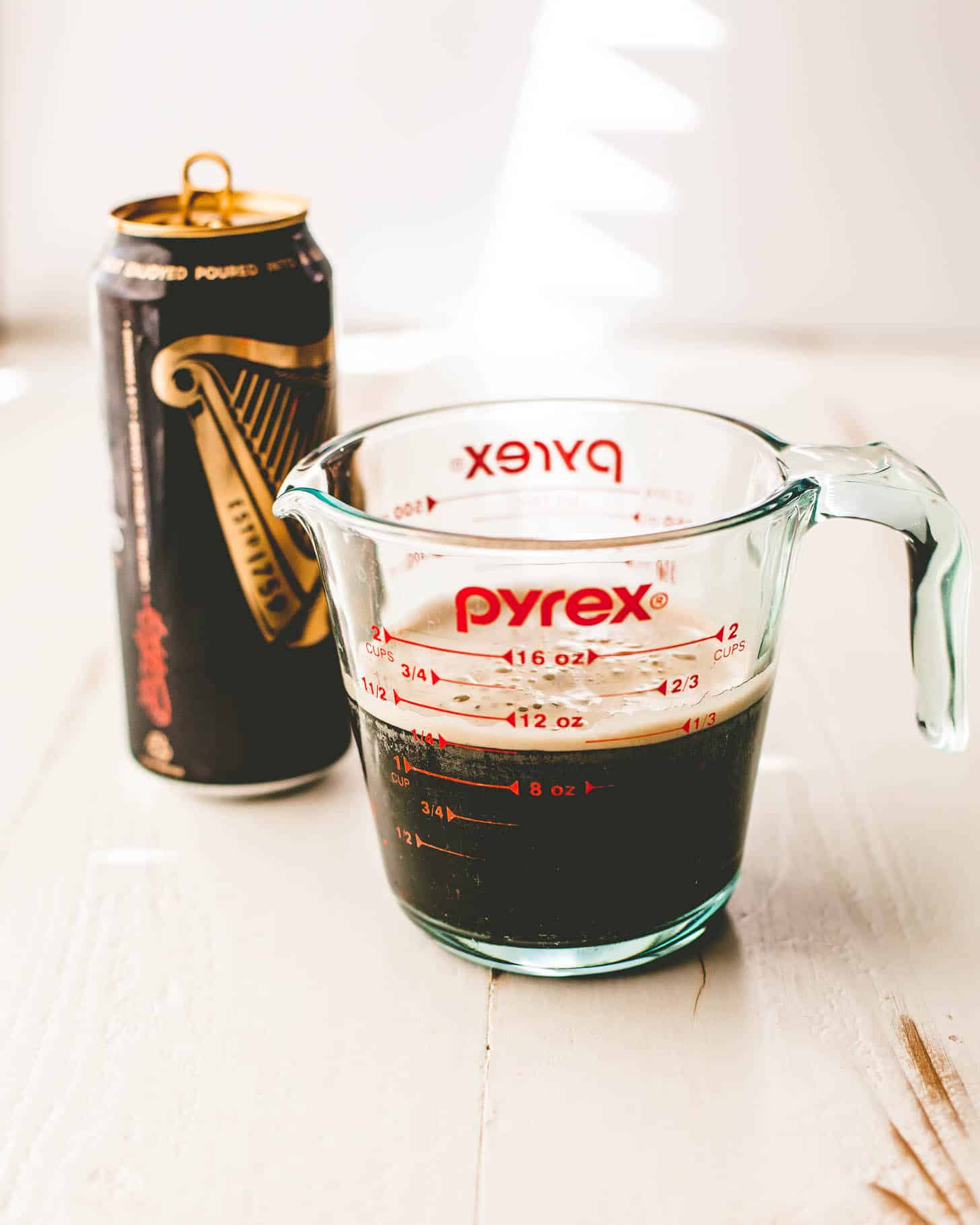 Guinness stout in a glass measuring cup on a grey countertop