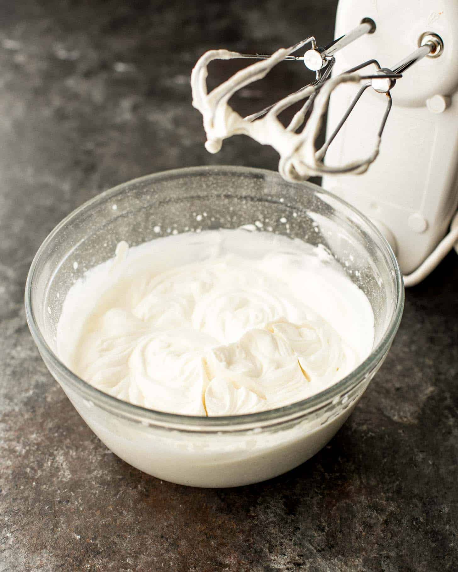 mixing bowl with icing next to a hand mixer