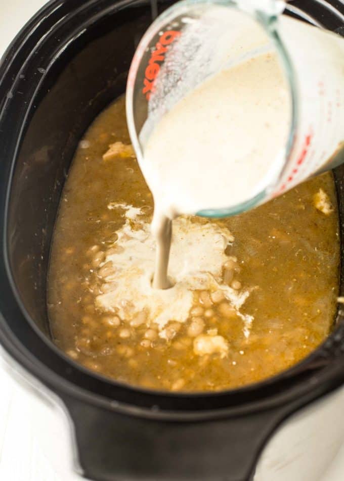 pouring sour cream into white chicken chili