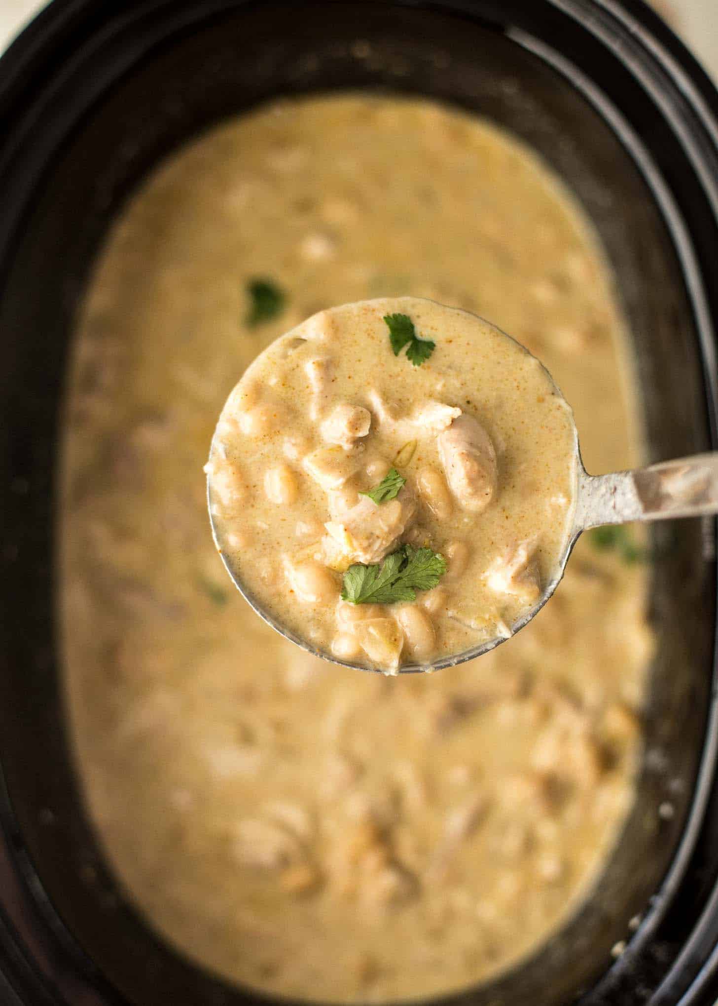 overhead image of a spoonful of slow cooker white chicken chili over a slow cooker