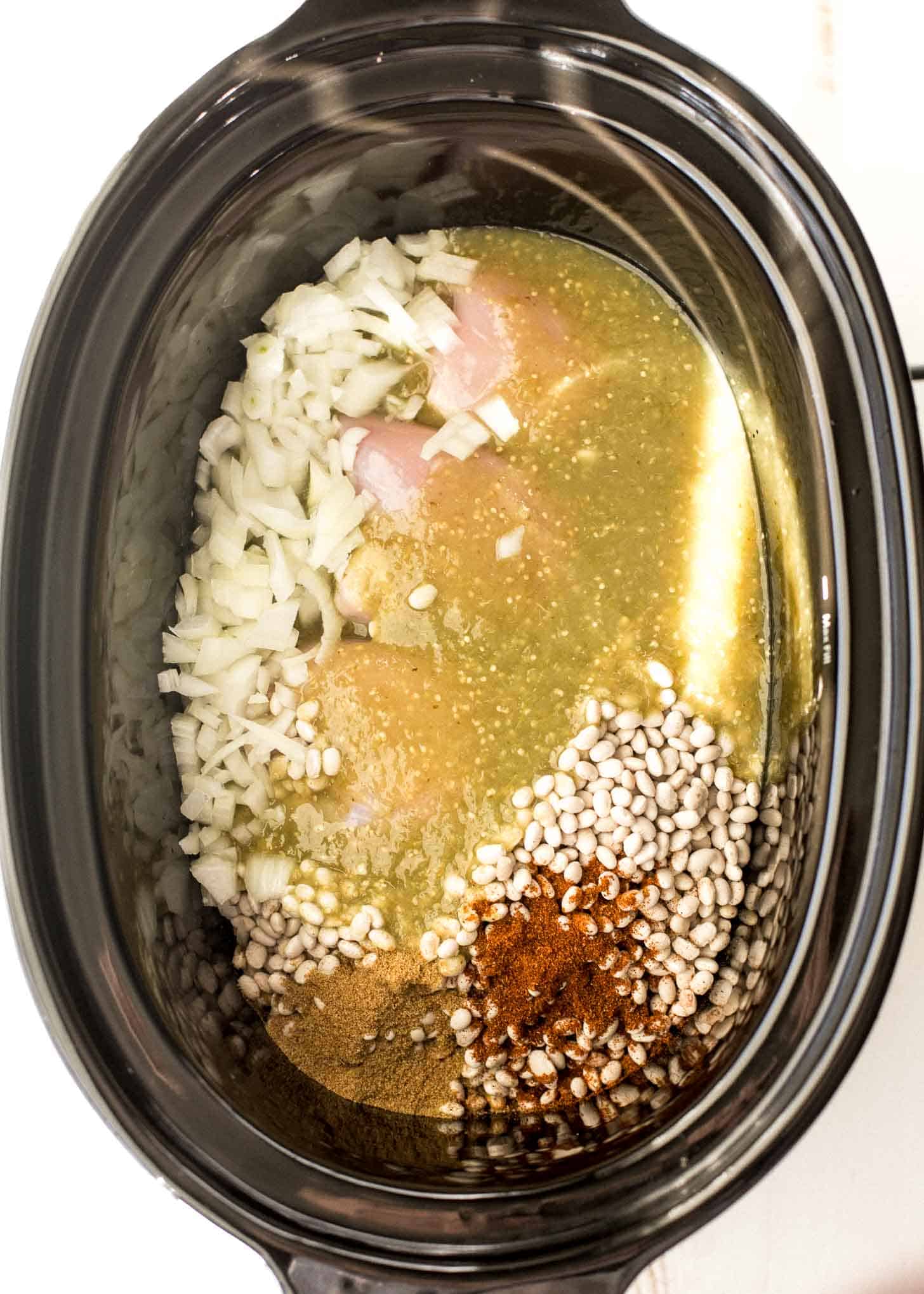 overhead image of white chicken chili ingredients in slow cooker