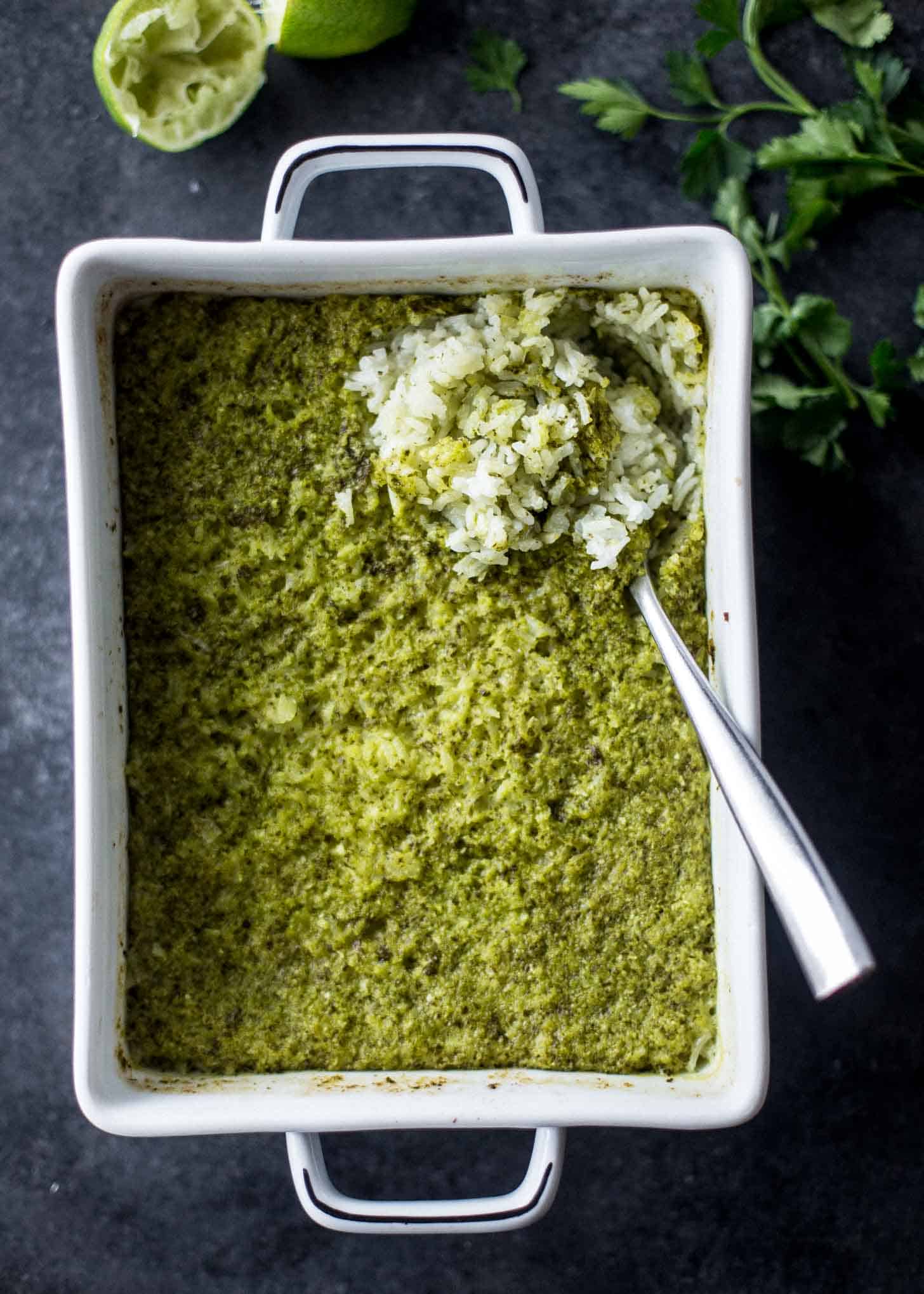 Baked Green Rice in a white baking dish with a spoon