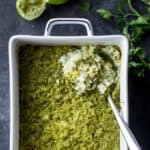 baked green rice in a white baking dish with a spoon