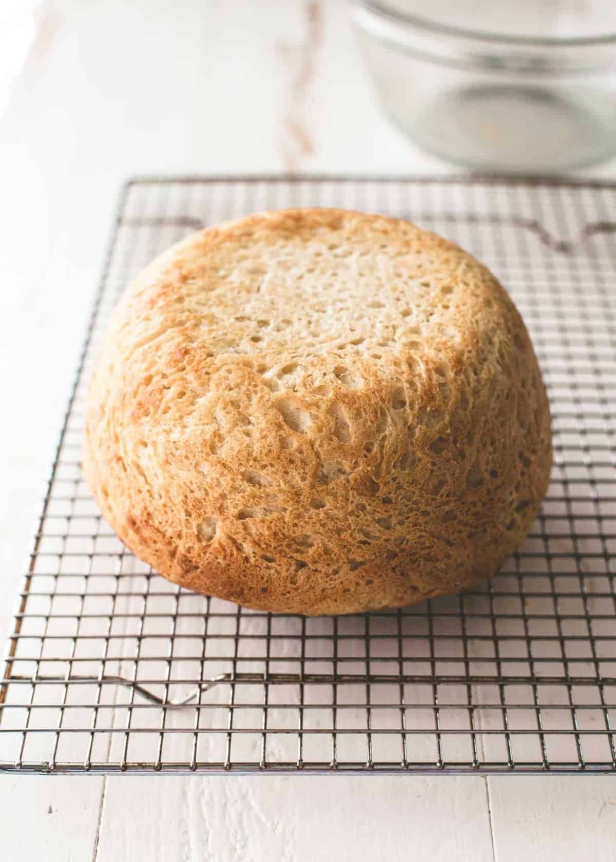a round loaf of no knead everyday bread on a cooling rack
