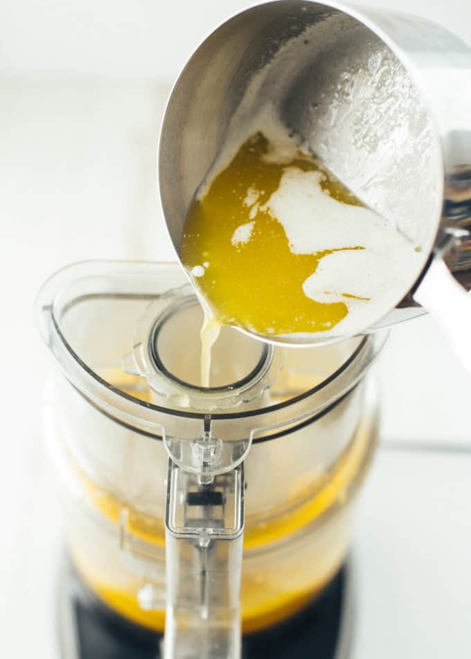 pouring melted butter into a food processor