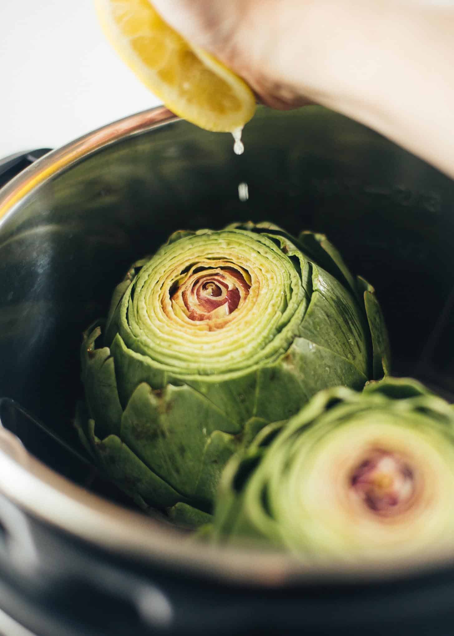 squeezing a lemon over artichokes in an instant pot