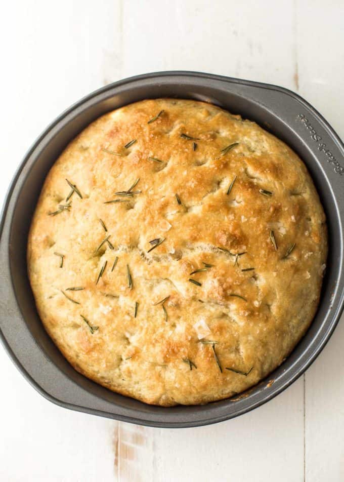 No knead focaccia in a round pan on a white background