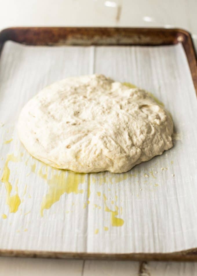 no knead focaccia dough on a parchment lined sheet pan
