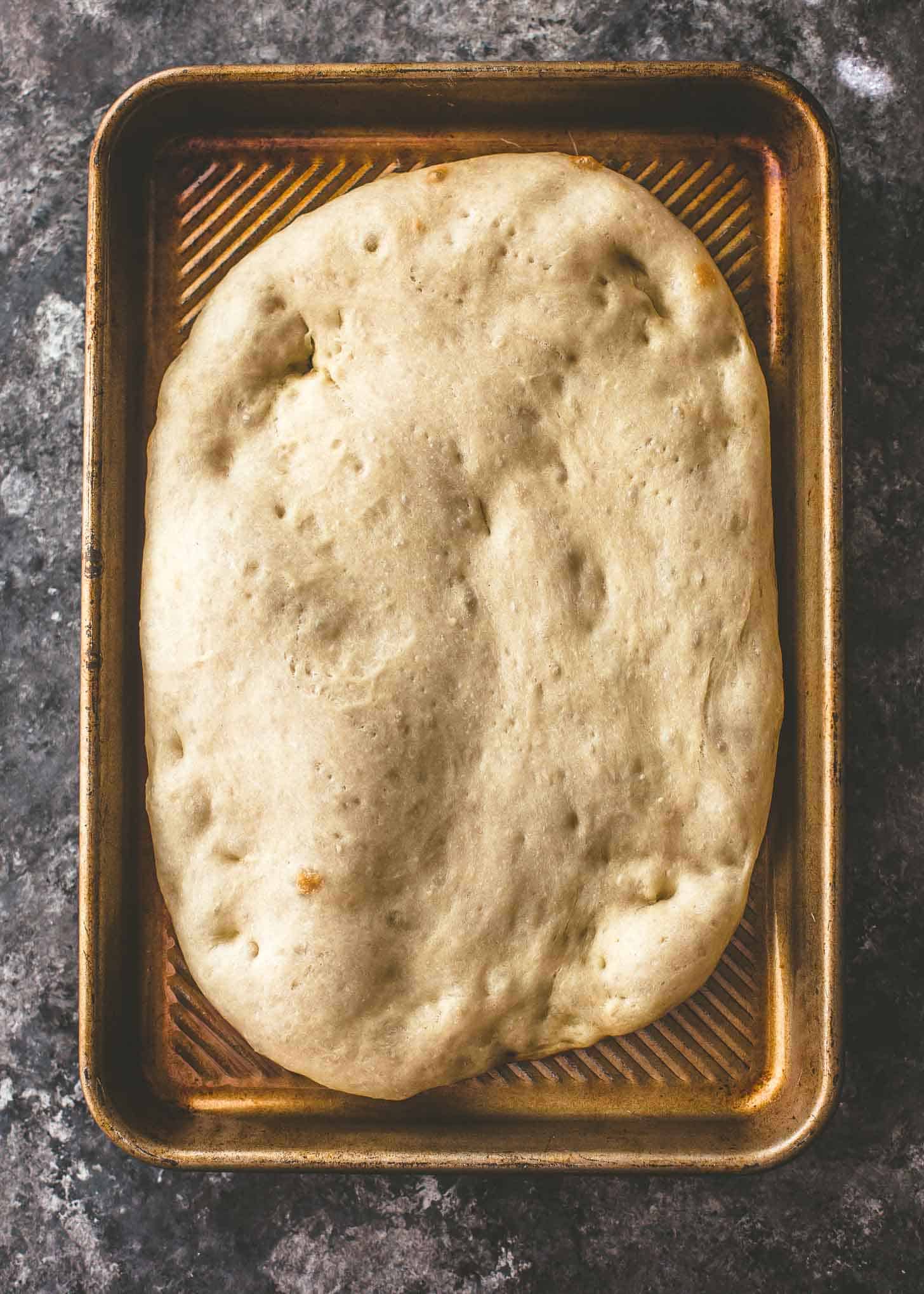 overhead image of baked No Knead Pizza Dough on a sheet pan