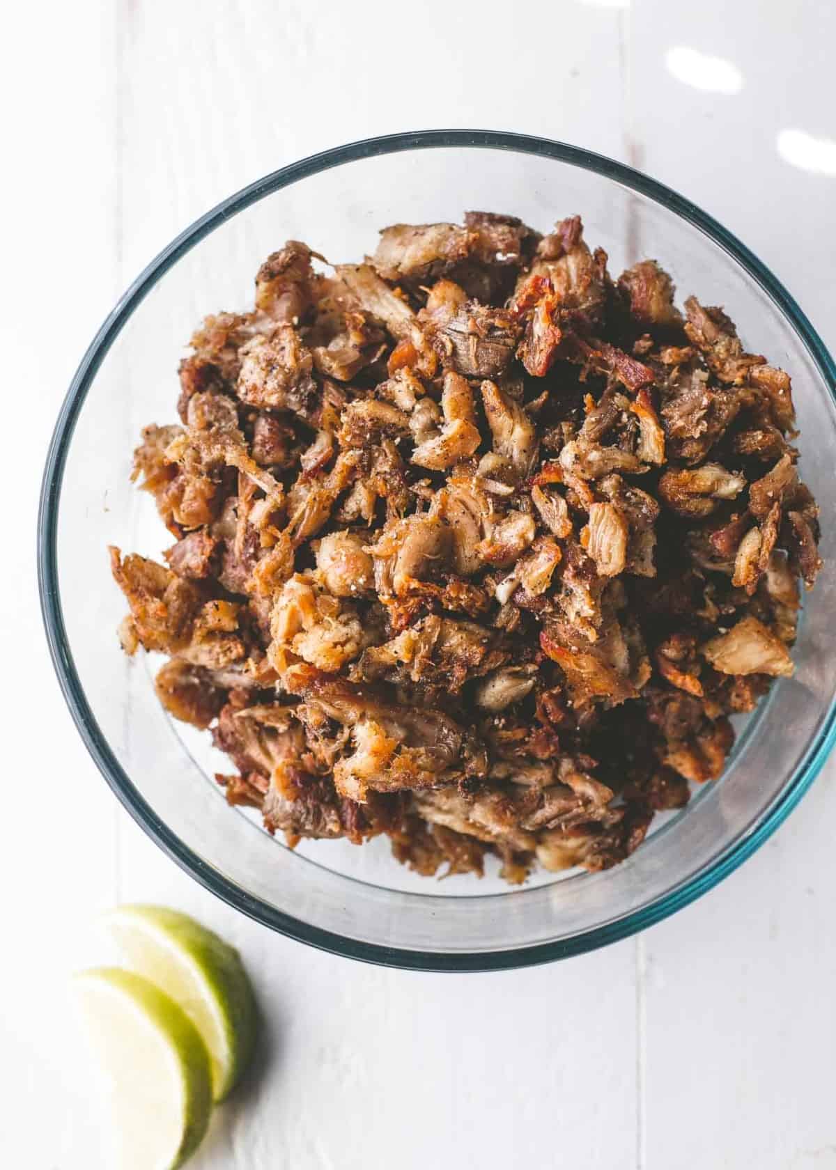 Slow cooker chicken carnitas in a clear glass bowl
