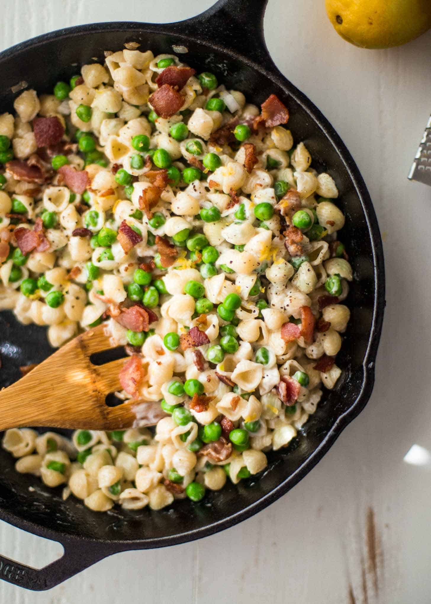 overhead image of Creamy shells with peas and bacon in a skillet