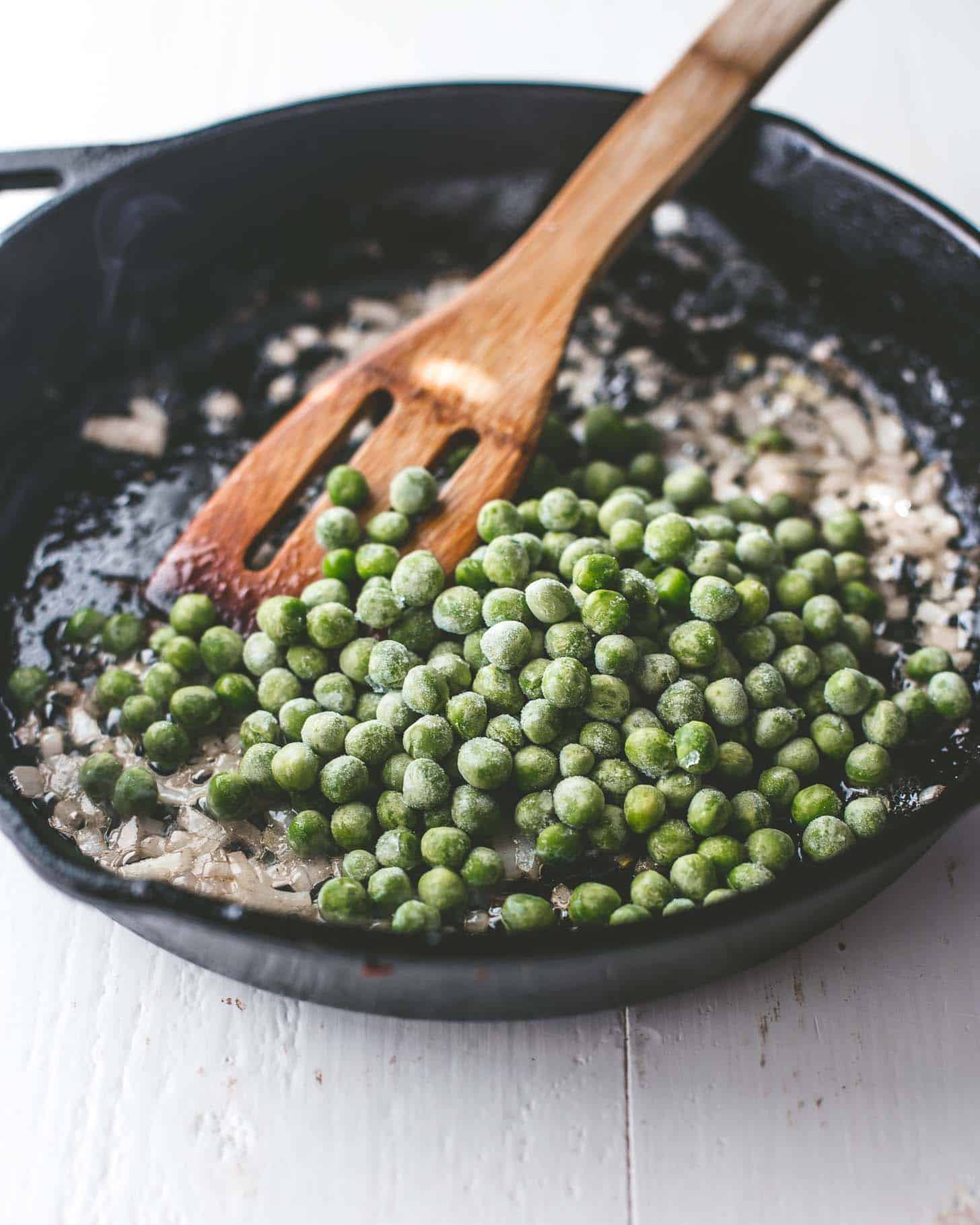 stirring peas in a cast iron skillet