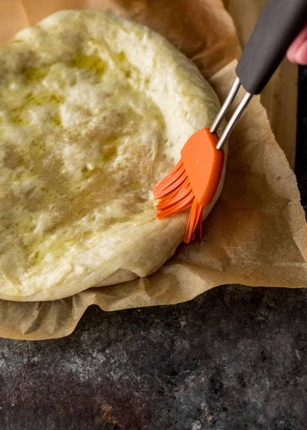 brushing pizza dough with olive oil