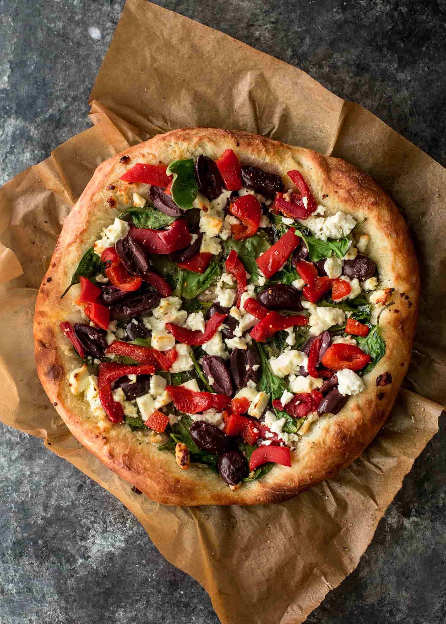 overhead image of a Greek Pizza on a piece of parchment paper