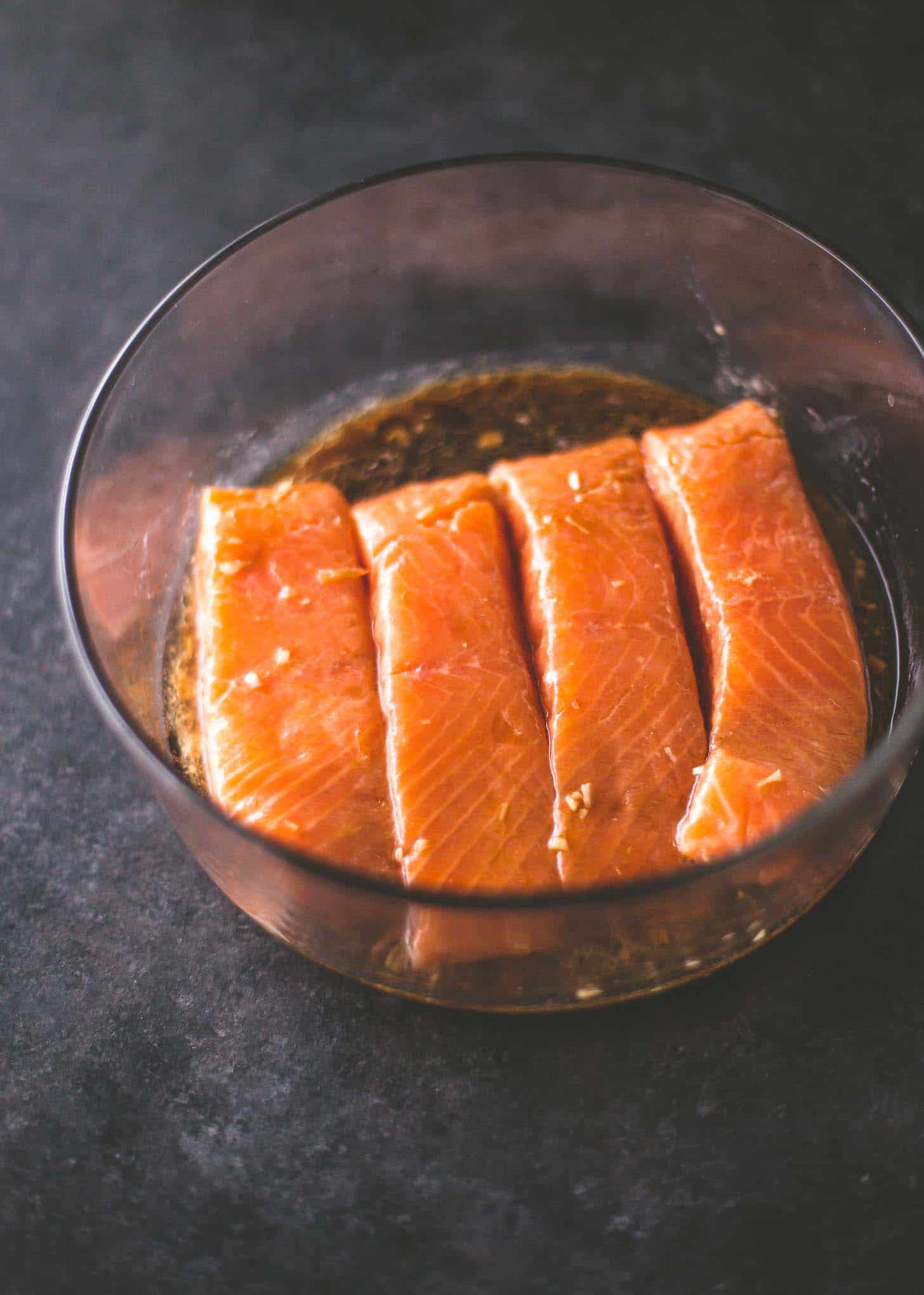 salmon marinating in a clear bowl