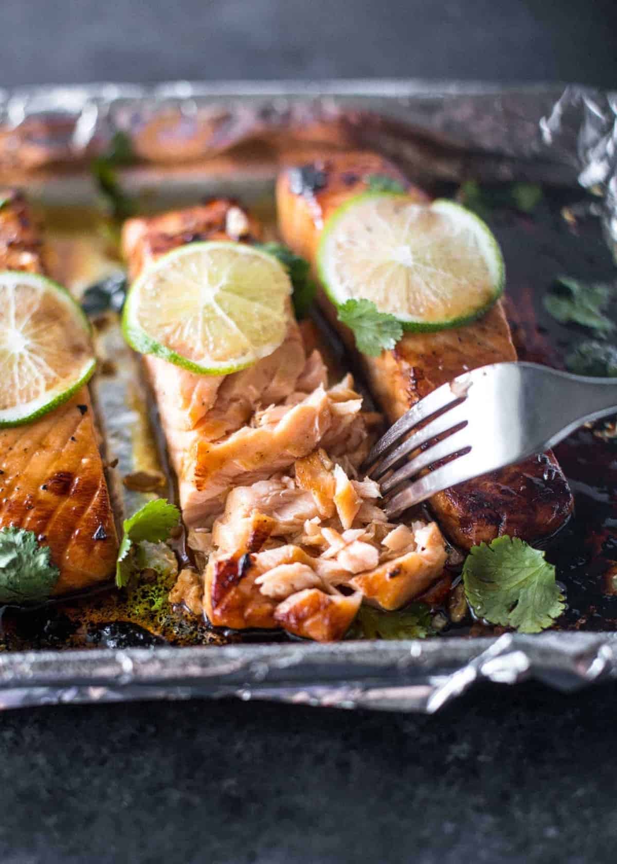 honey lime salmon with a fork on a sheet pan lined with foil