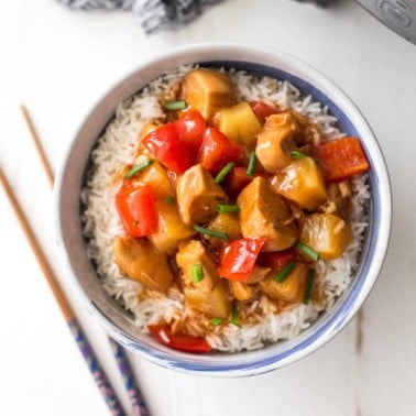 instant pot sweet and sour chicken over rice in a bowl next to chopsticks