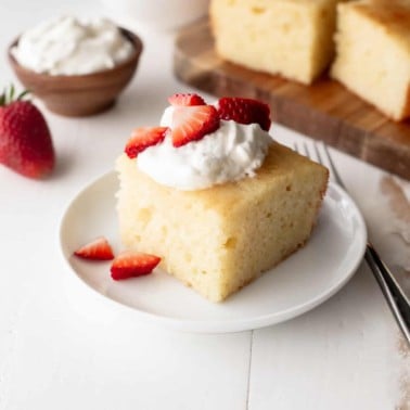 vanilla semolina cake on a white plate with strawberries and cream