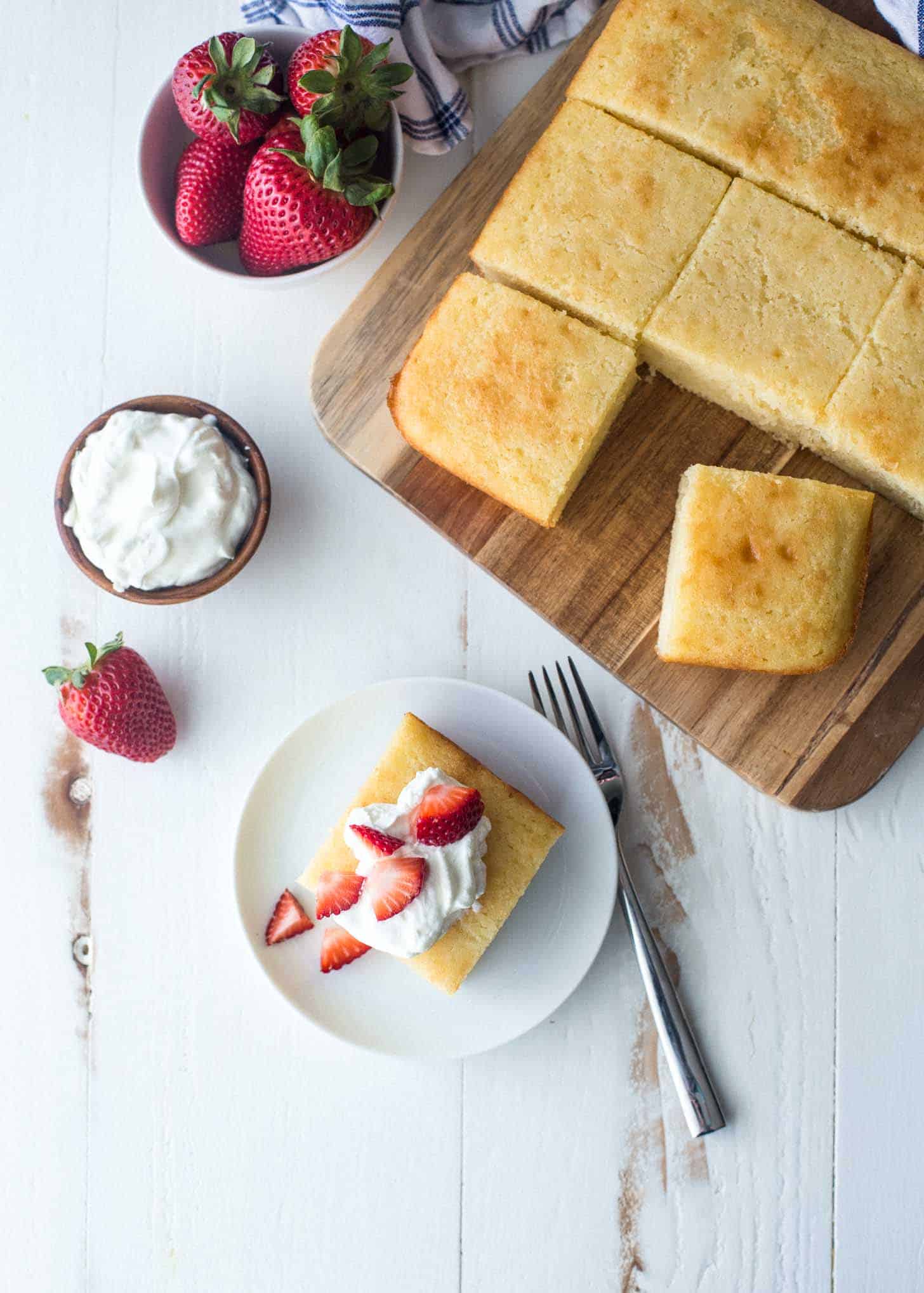 a slice of semolina yogurt cake on a plate next to the whole cake