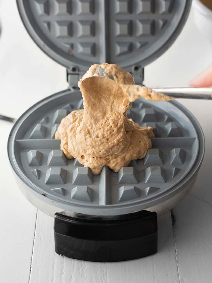 adding waffle batter to a waffle maker