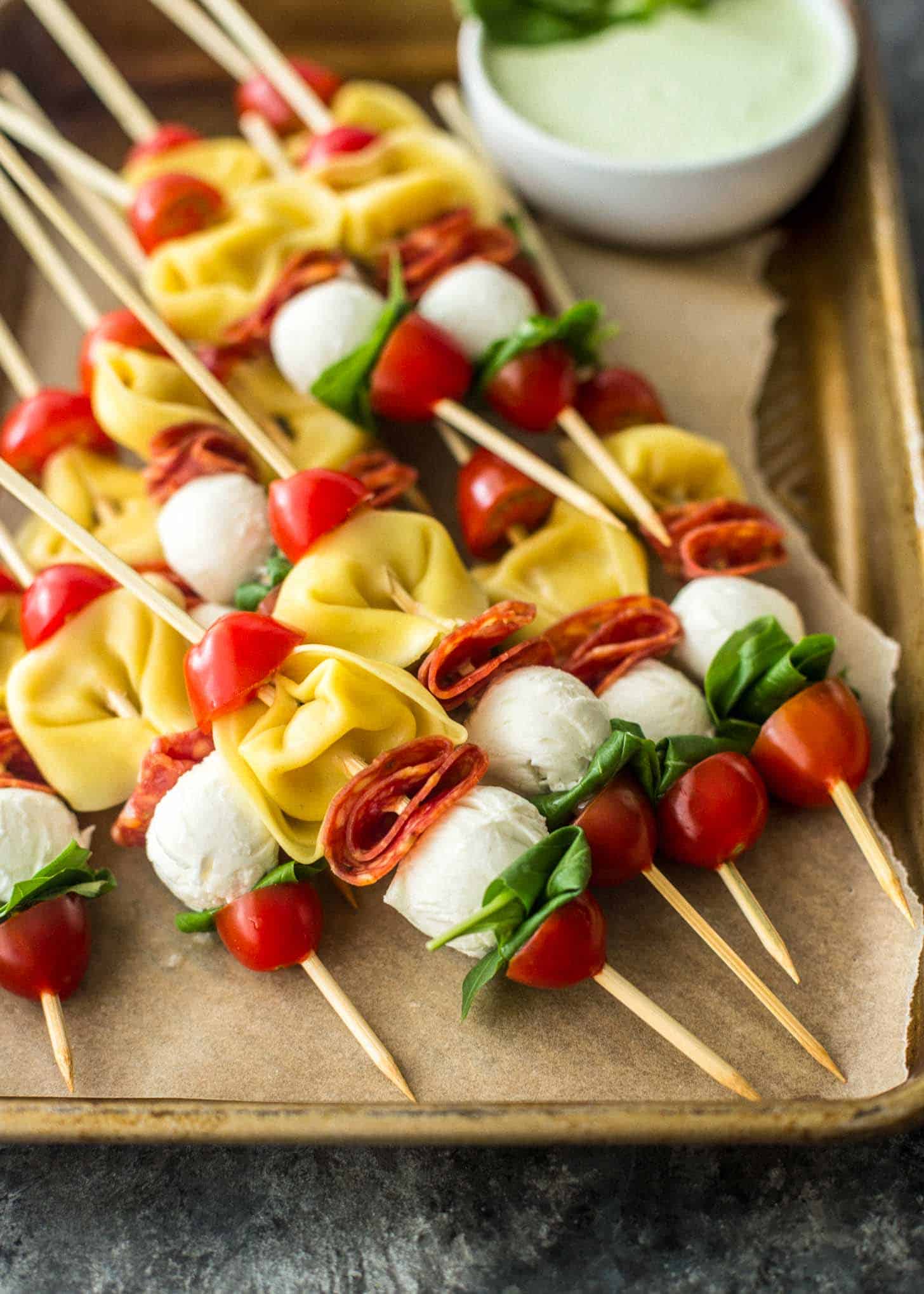 close up image of Pasta Salad Skewers on a parchment lined sheet pan