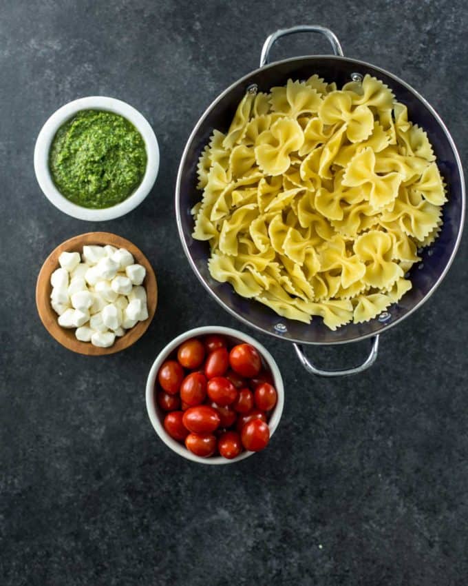 pasta, mozzarella, tomatoes and pesto on a grey countertop