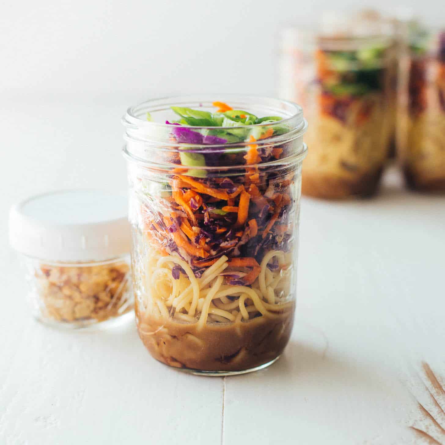 Sesame noodle salad in a mason jar on a white table