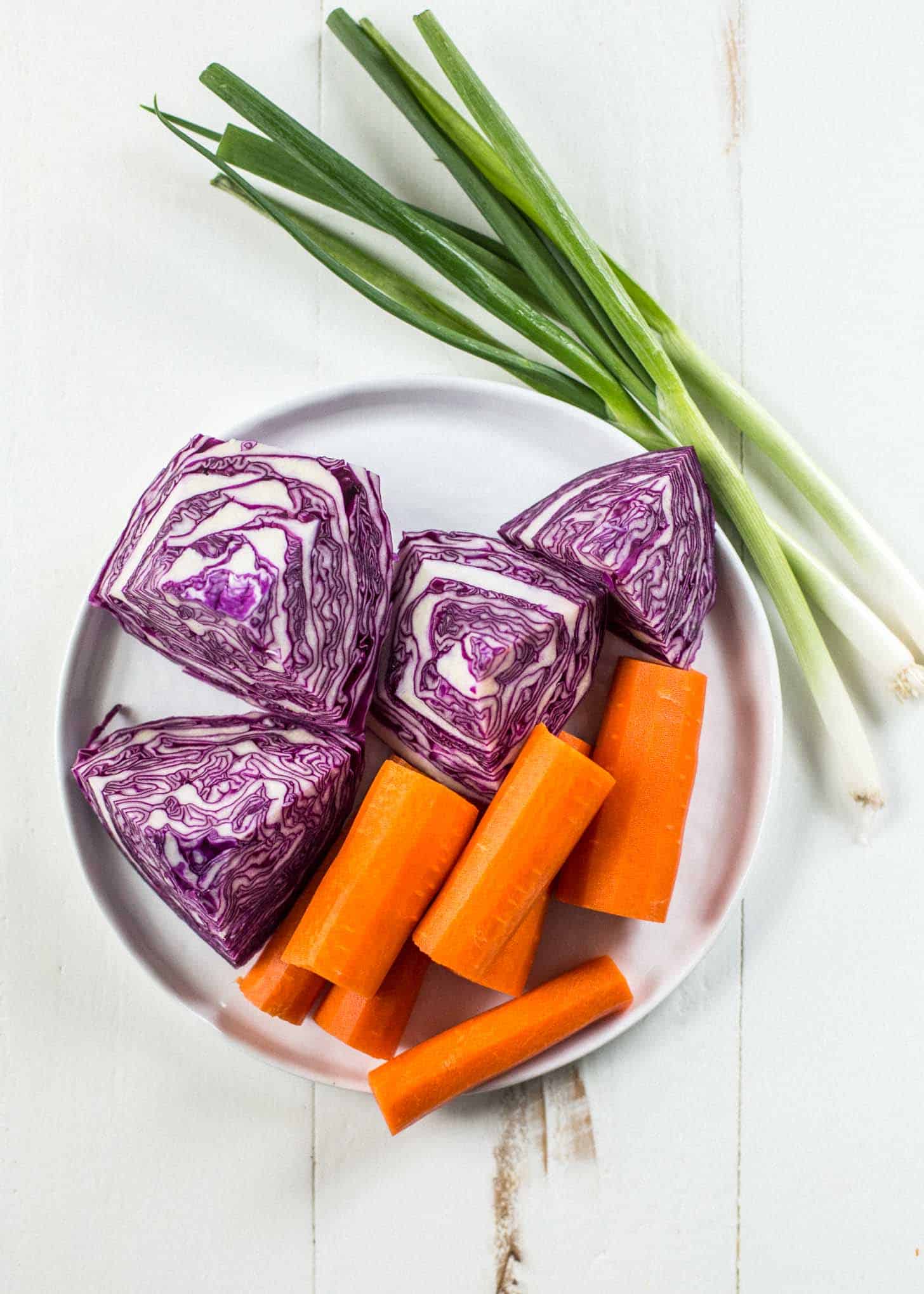 cabbage, carrots and green onions on a white plate on a white table