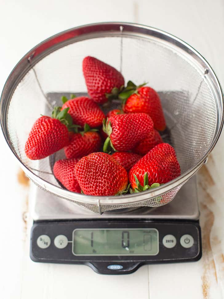 fresh strawberries in a strainer on a kitchen scale