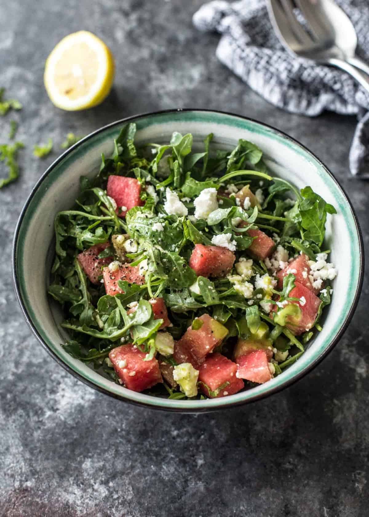 watermelon, feta and arugula salad in a blue and white bowl