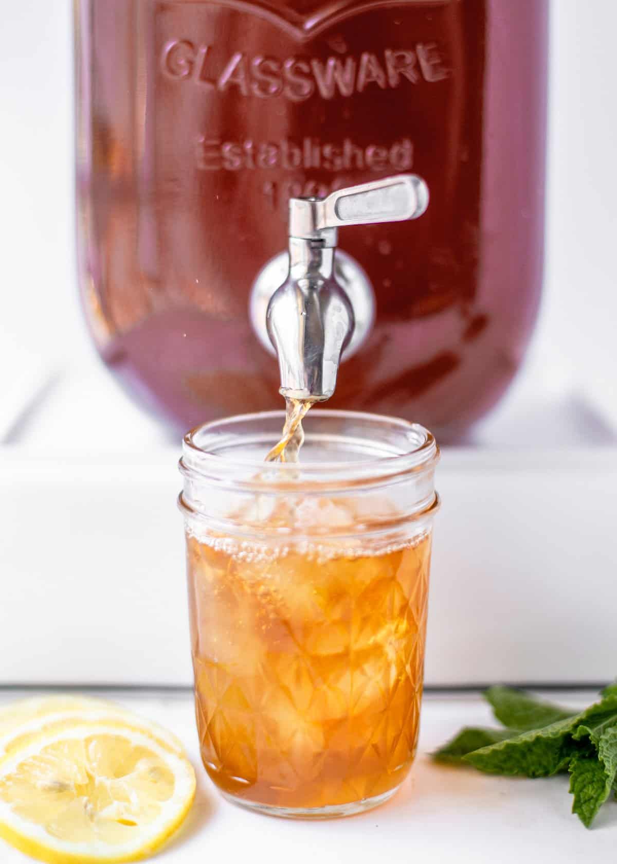 bourbon sweet tea being poured from a glass container into a mason jar