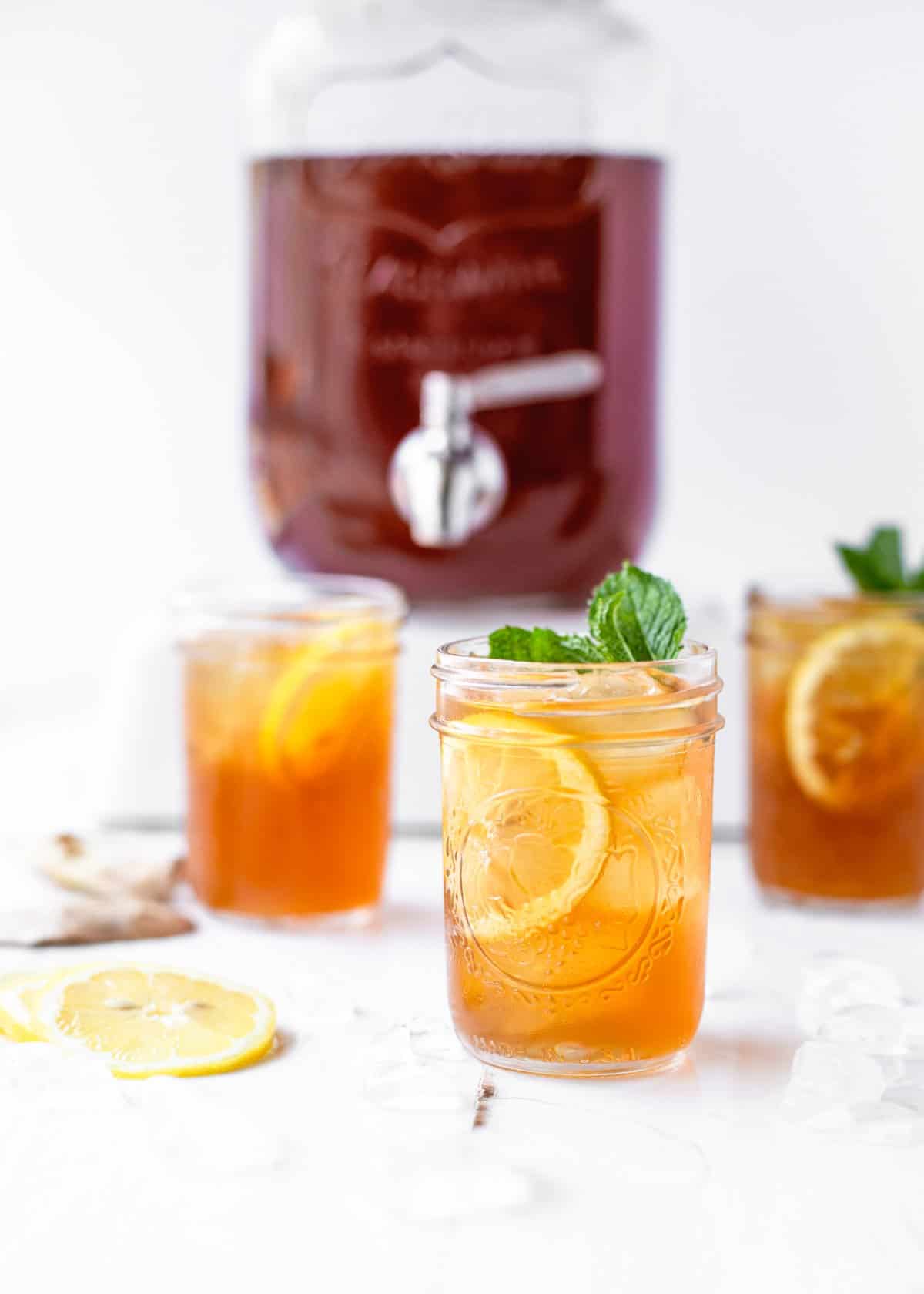 three mason jars filled with ice, lemons, and bourbon sweet tea cocktail