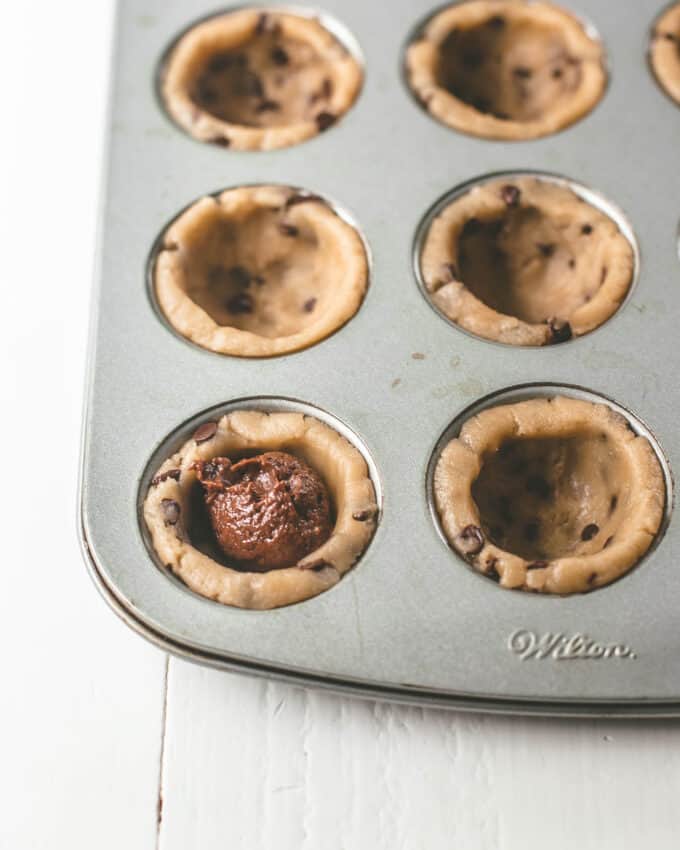brownie batter inside cookie dough in a muffin tin