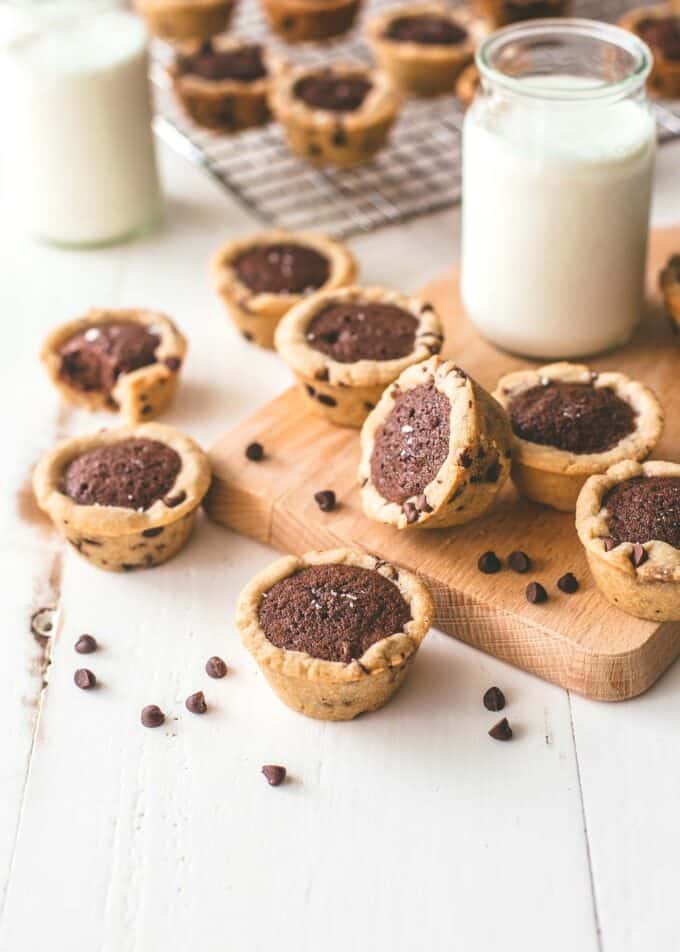 chocolate chip brownie tarts on a wood cutting board with a glass of milk