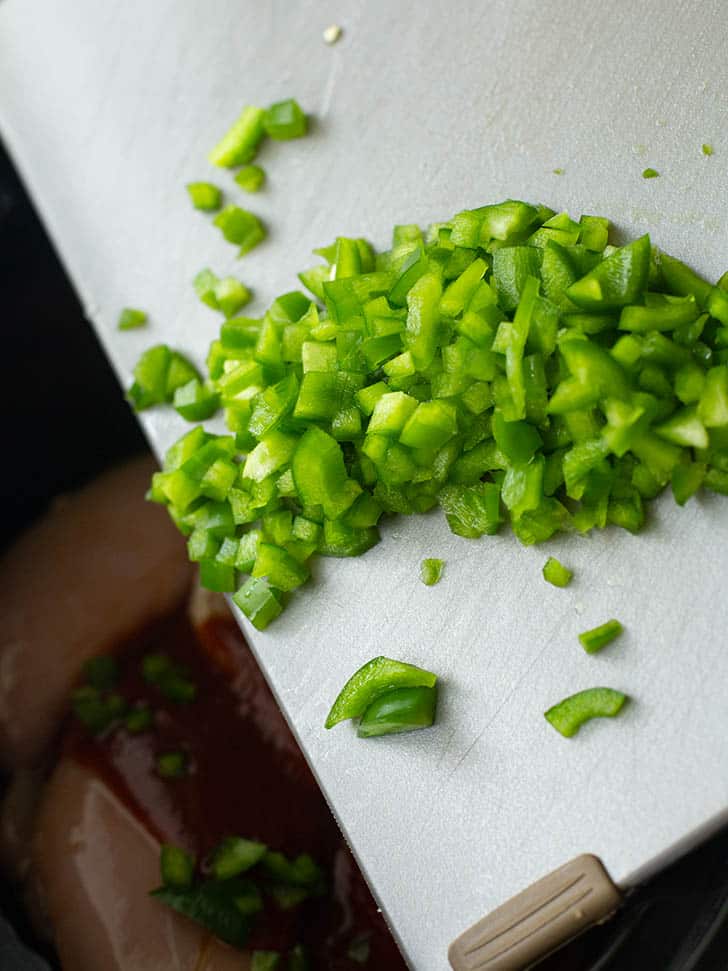 overhead image of diced green peppers on a white cutting board