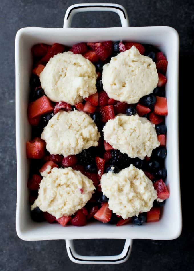 berries with cobbler dough on top in a baking dish