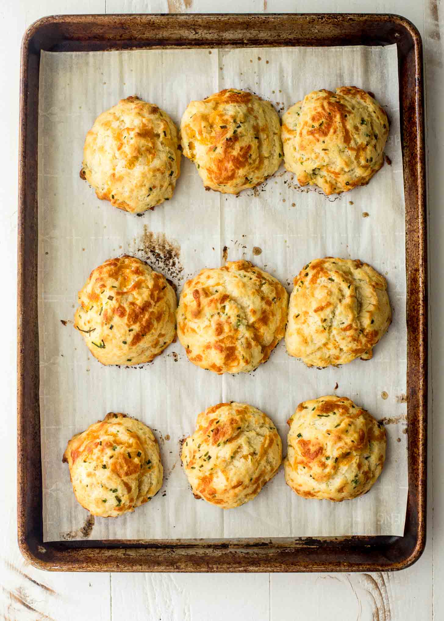 cheddar drop biscuits on a parchment lined sheet pan
