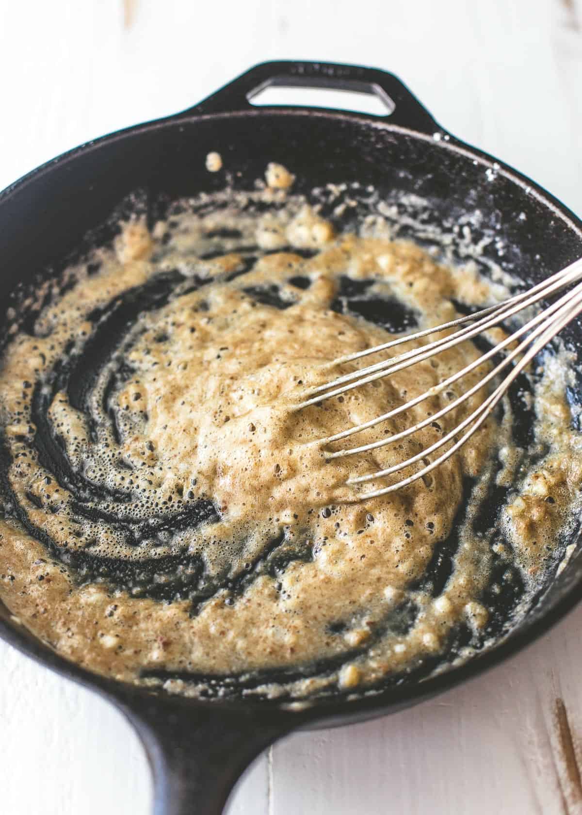 stirring sauce in a cast iron skillet