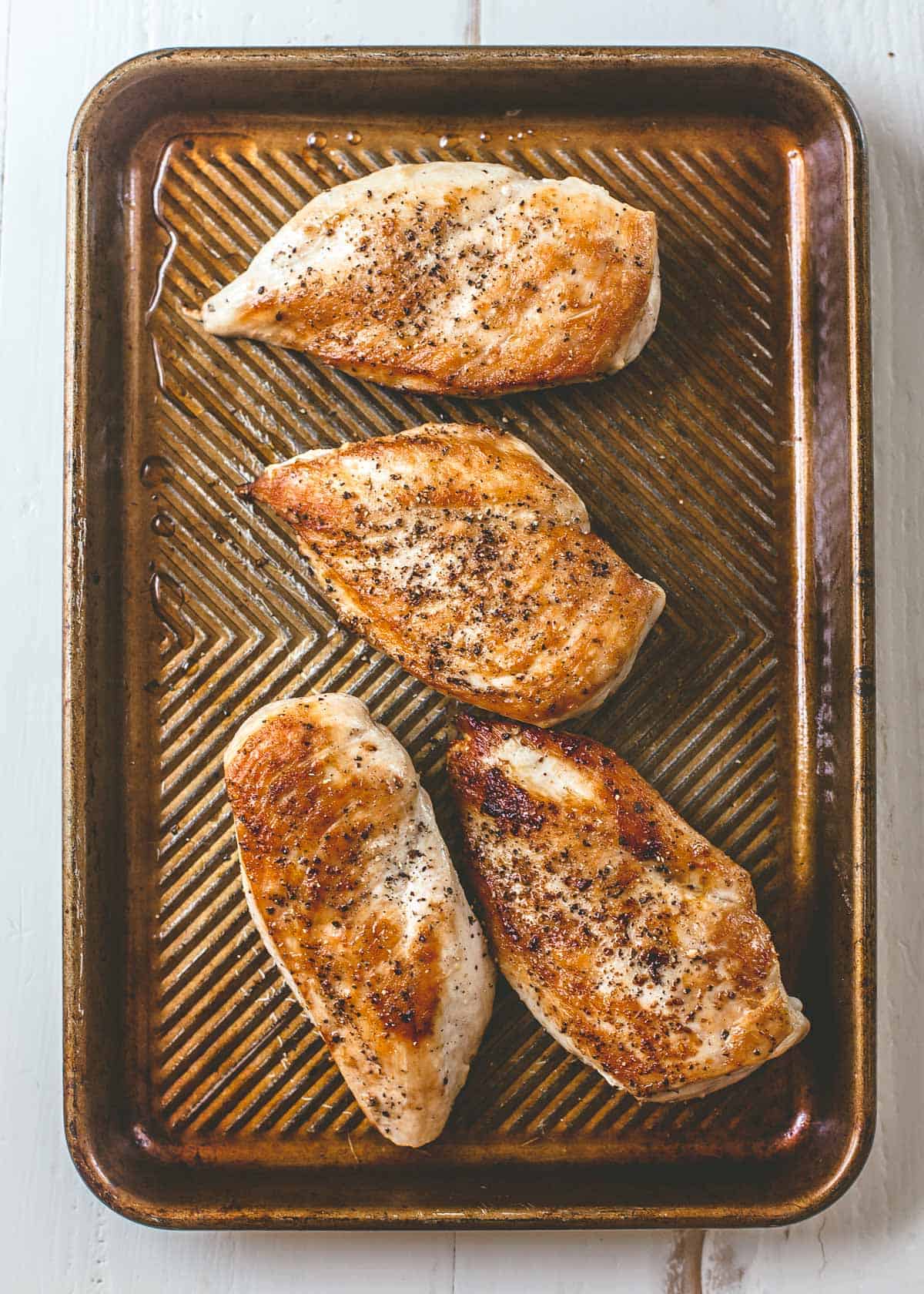 cooked chicken breasts on a sheet pan