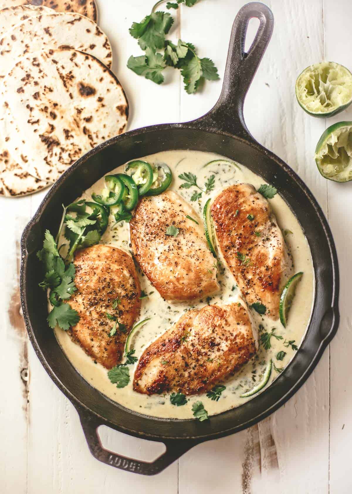 chicken breast in a skillet with creamy cilantro lime sauce