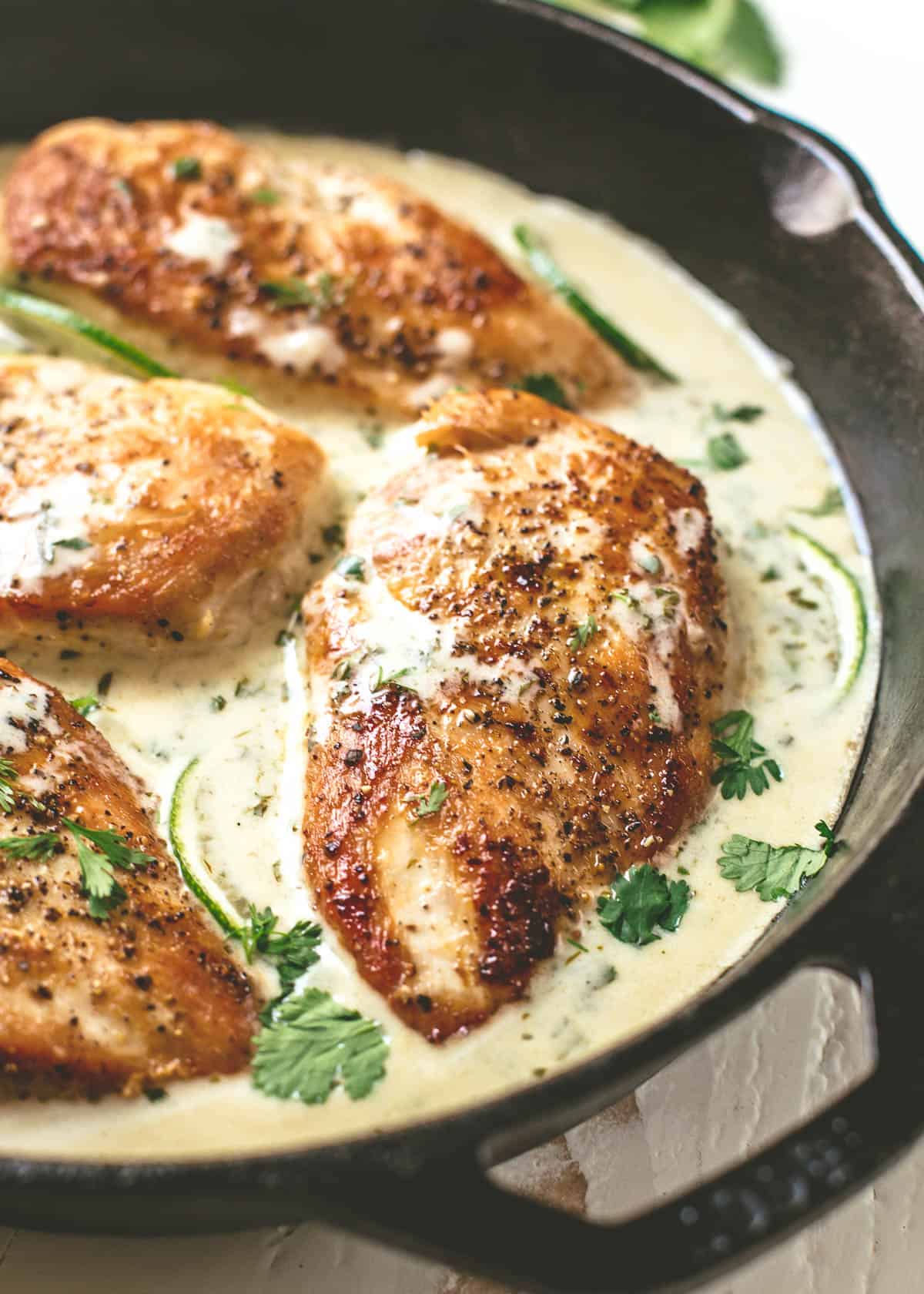 chicken breast in a skillet with creamy cilantro lime sauce