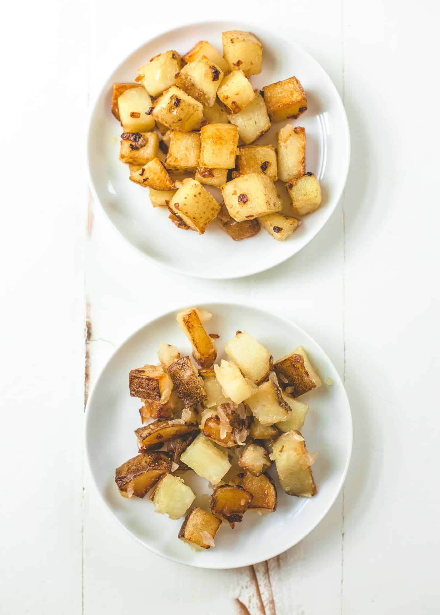 2 white plates of home fries on a white table