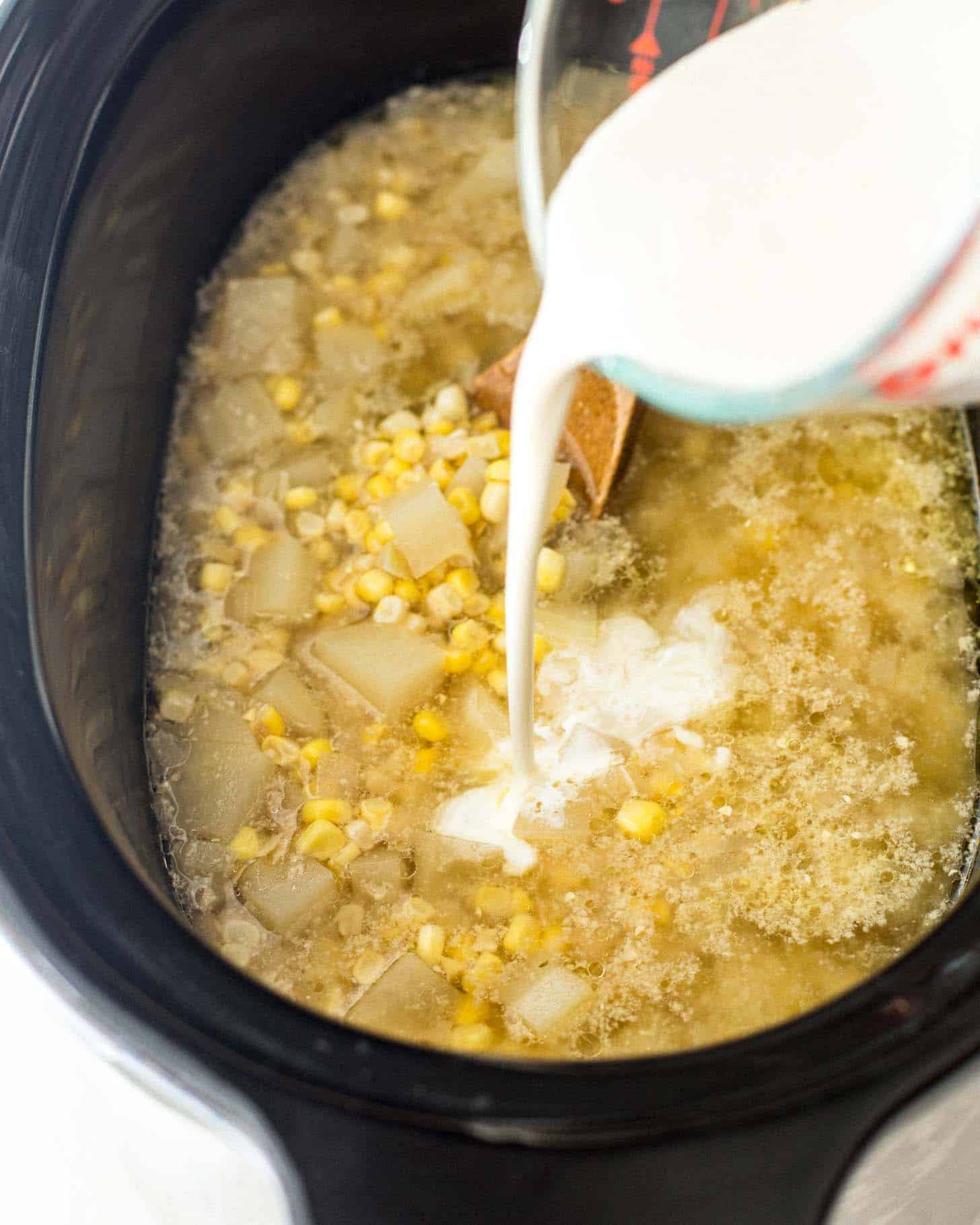 adding cream to the chowder in a slow cooker