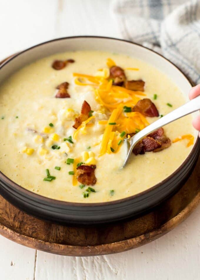 a bowl of corn chowder on a wooden tray