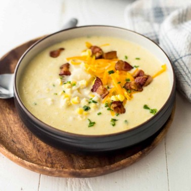 a bowl of corn chowder topped with cheese and bacon