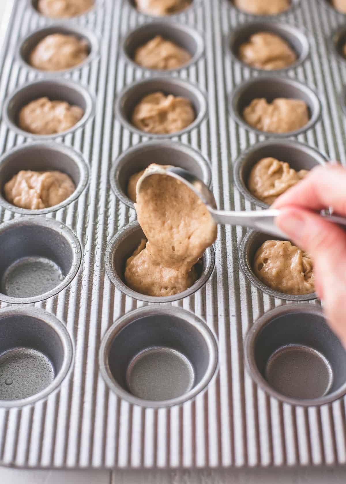 spooning mixture into muffin tin
