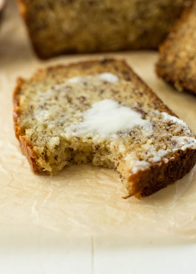 a slice of buttered banana bread with a bite taken out