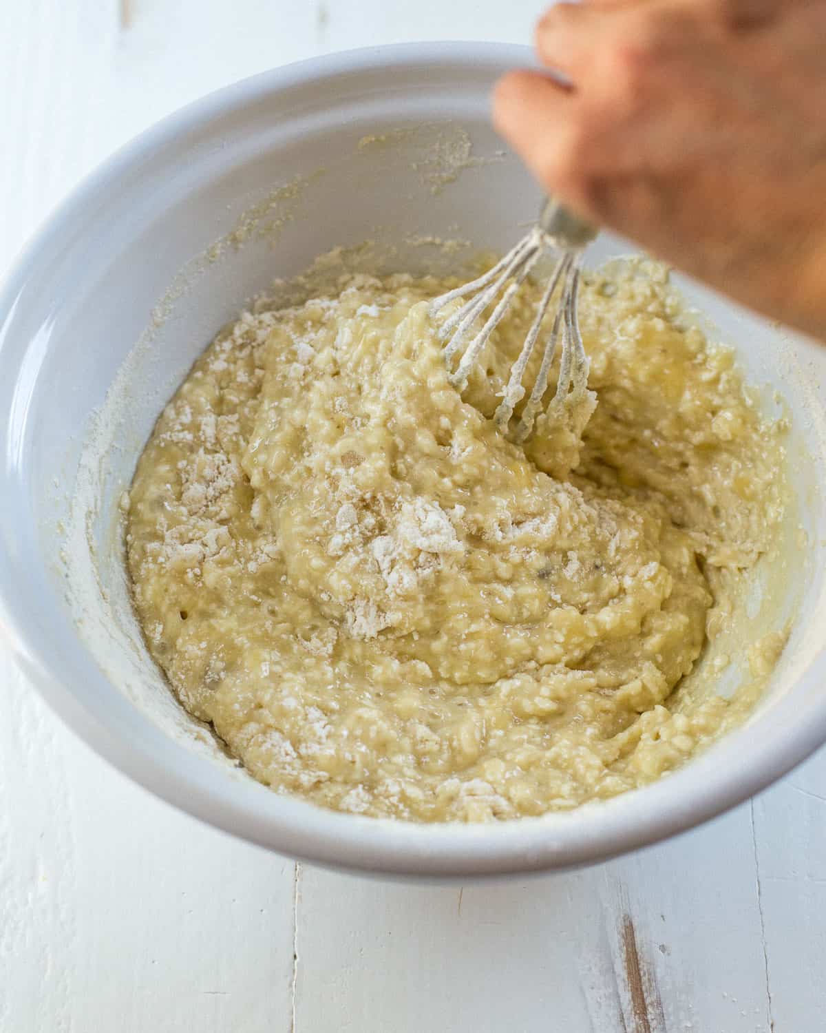 overhead image of a whisk mixing ingredients in a mixing bowl