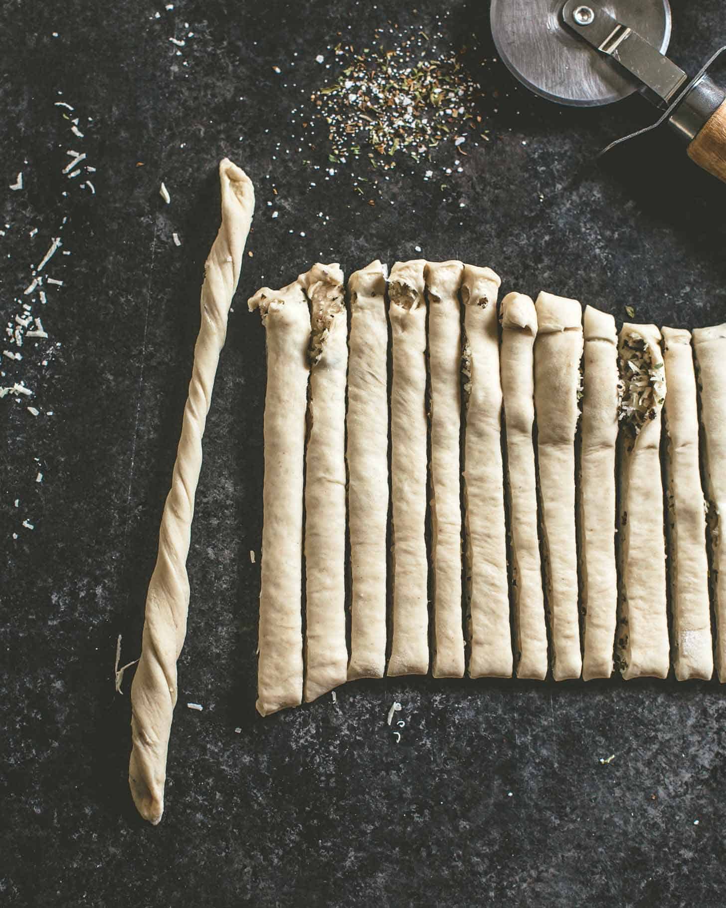 overhead image of raw breadsticks on a grey countertop